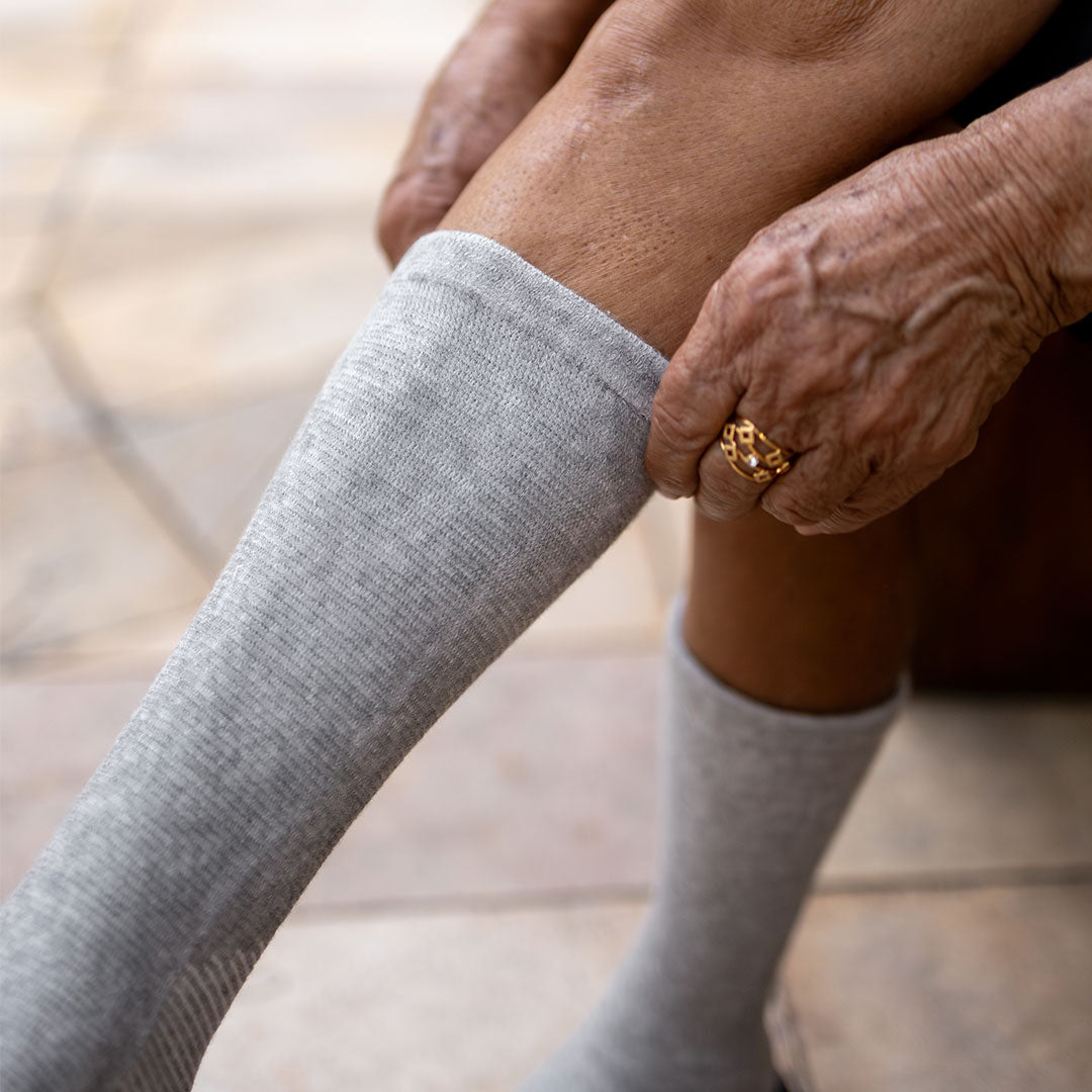 Gray bamboo compression foot sleeve worn while seated