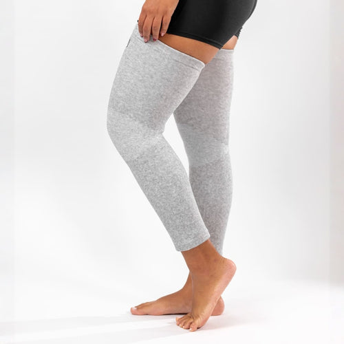 Gray full-leg compression sleeve worn while bending the knee